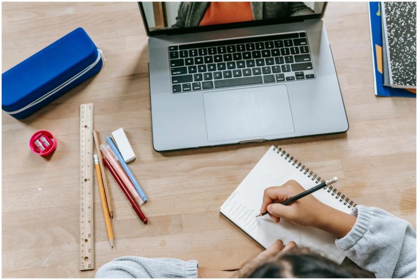 Top view of crop anonymous smart pupil writing inf