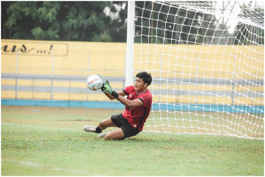 A goalkeeper in action saving the ball during a so
