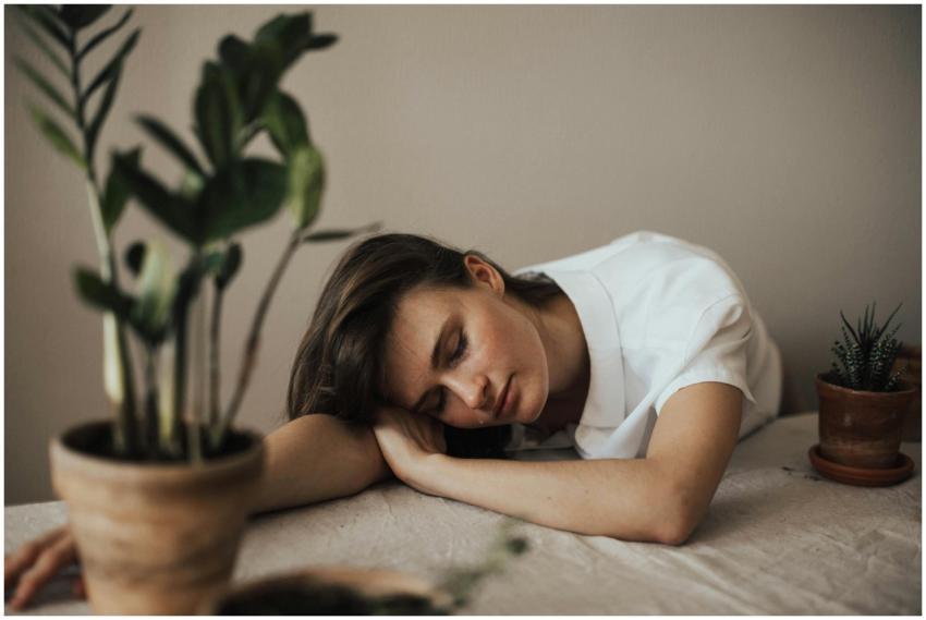 A woman peacefully resting her head on a table sur
