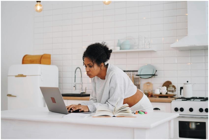 A woman with afro hair works on her laptop in a st