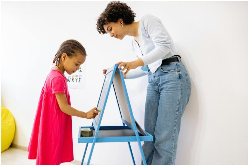 A child and teacher interact at a chalkboard, fost