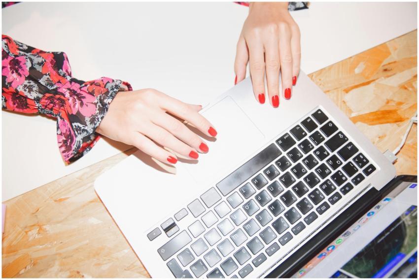 Close-up of woman's hands typing on a laptop with