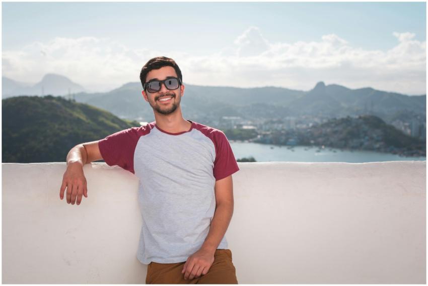 Young man in sunglasses leaning on a balcony with
