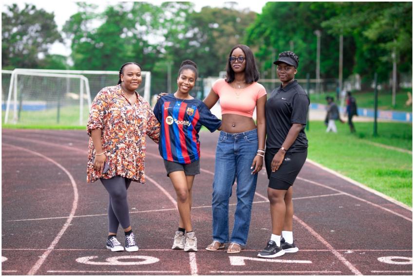 Four women pose confidently on a running track, ex