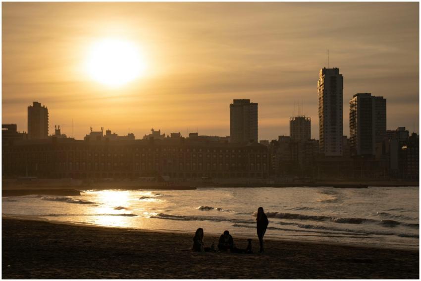 Silhouetted figures on Mar del Plata beach at suns