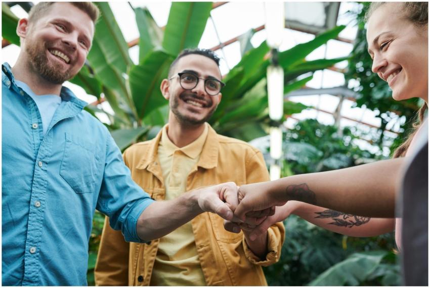 Three friends sharing a joyful fist bump in a lush