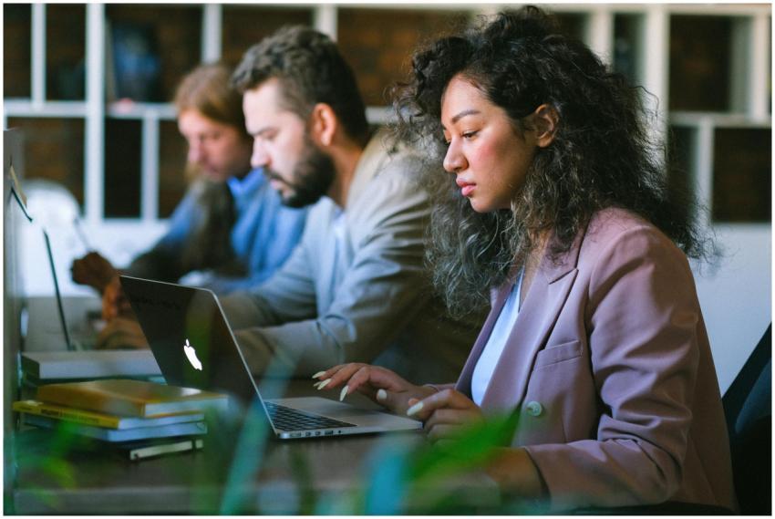 Focused young professionals collaborate on laptops