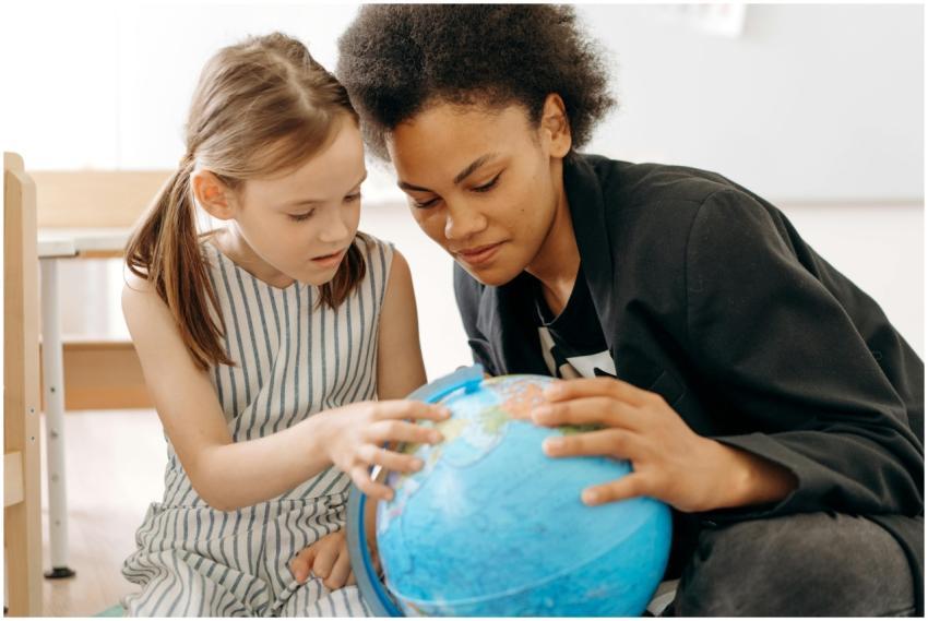 Child and teacher exploring a globe, symbolizing e
