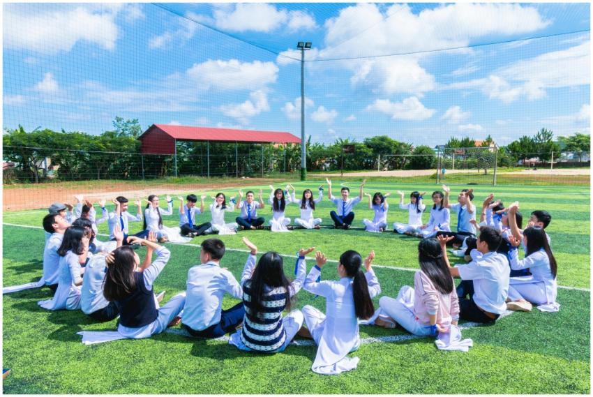 Students seated in a circle on a school field enga