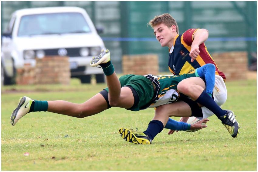 Two young athletes engaged in a dynamic rugby tack