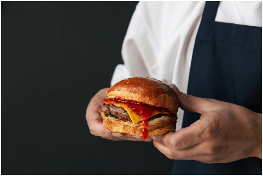 A savory cheeseburger with dripping ketchup held i