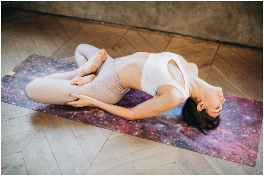 Woman practicing Matsyasana pose on a galaxy yoga
