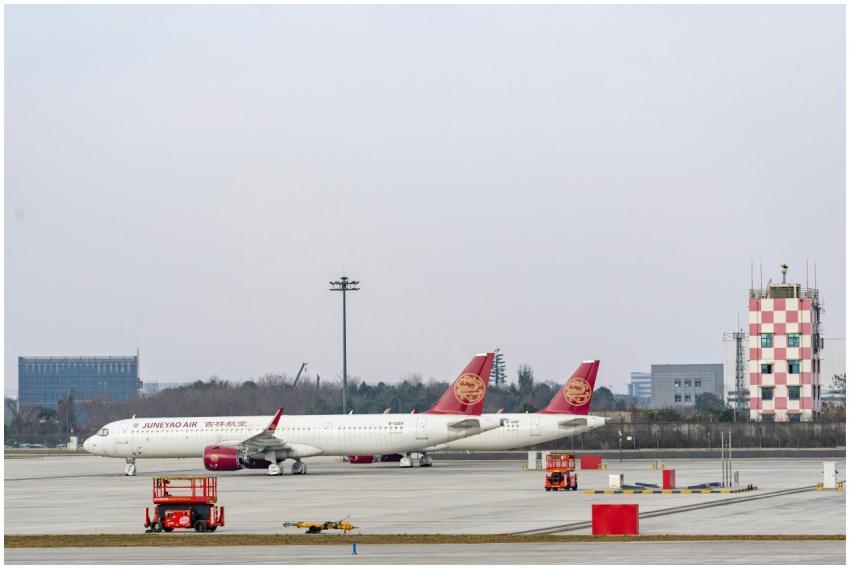 Two Juneyao Air planes parked on a clear day at an