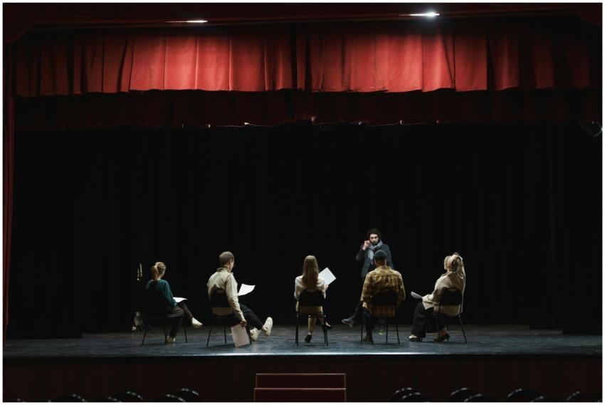 A group of actors rehearsing on a dimly lit stage