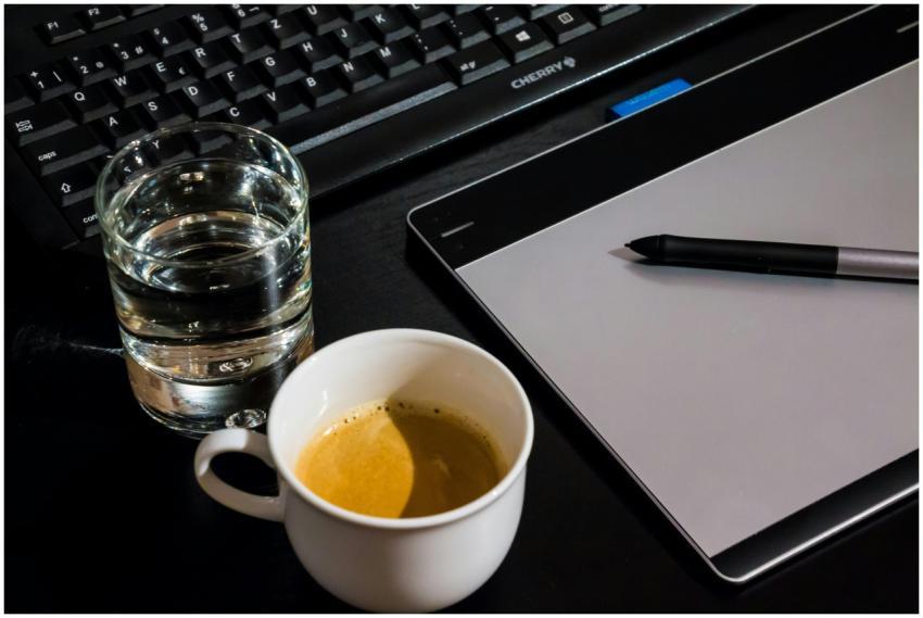 Office desk setup with a coffee cup, glass of wate