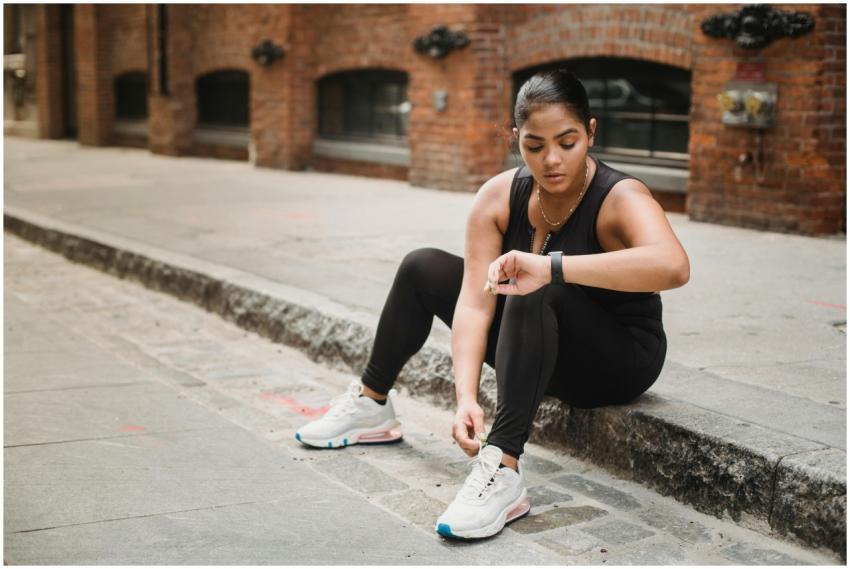 Woman in activewear checking smartwatch while sitt