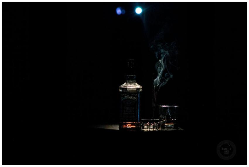 A dramatic whiskey bottle with smoke on a dark bac