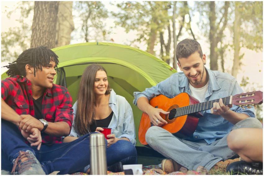 Group of friends having fun and playing guitar whi