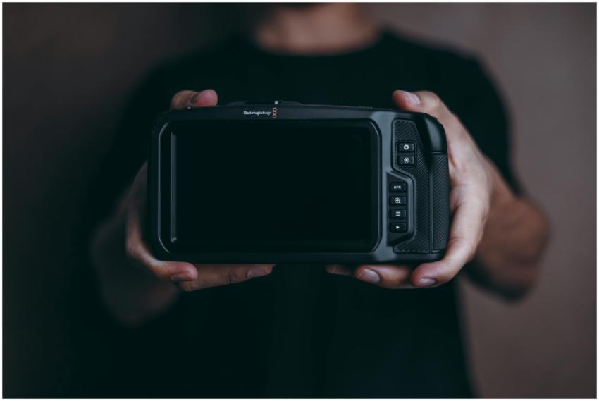 A person holding a modern digital camera in a clos