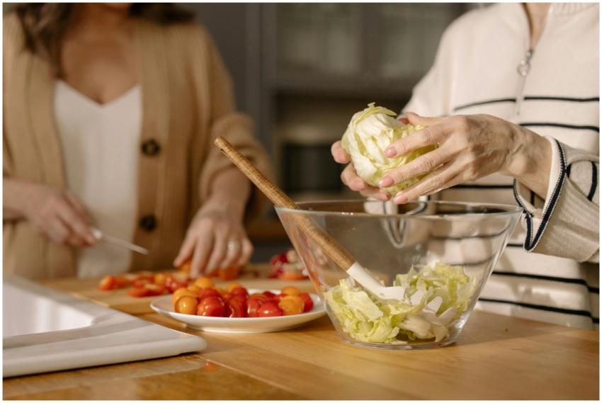 Two women chopping fresh vegetables for a salad in