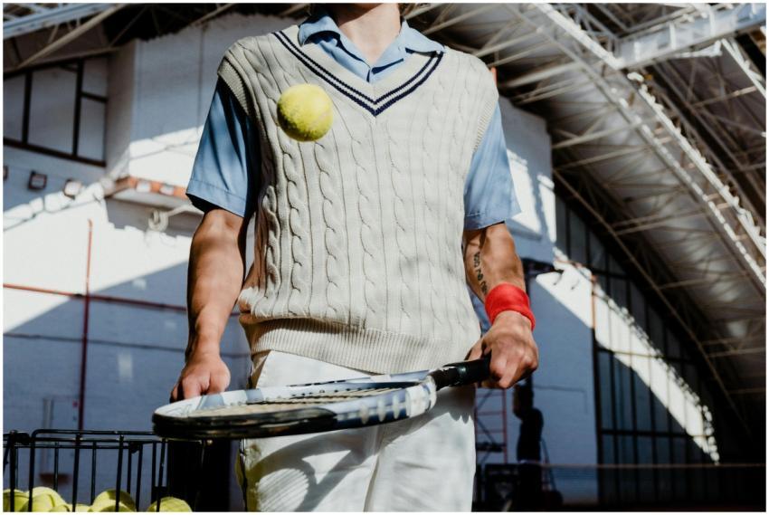A retro-clothed tennis player in an indoor court c