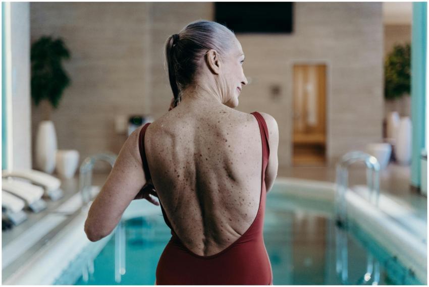 Senior woman in red swimsuit standing at indoor po