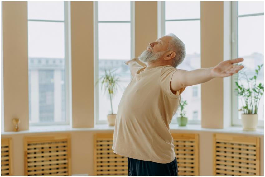Elderly man meditating with eyes closed, arms wide