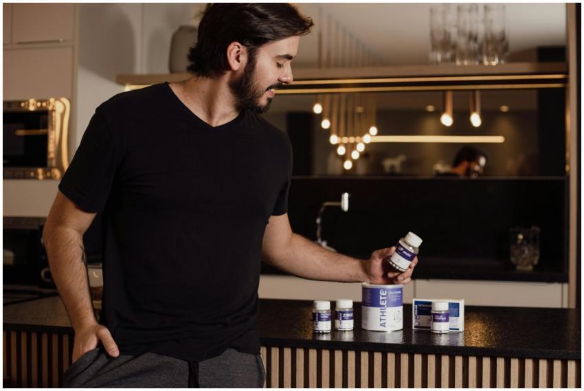 A man examines supplement bottles on a modern kitc