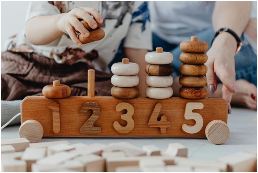 A child and adult playing with wooden number toys,