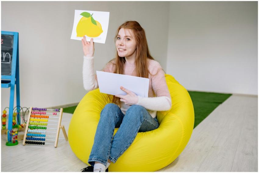 Smiling teacher sitting on a bean bag, holding edu