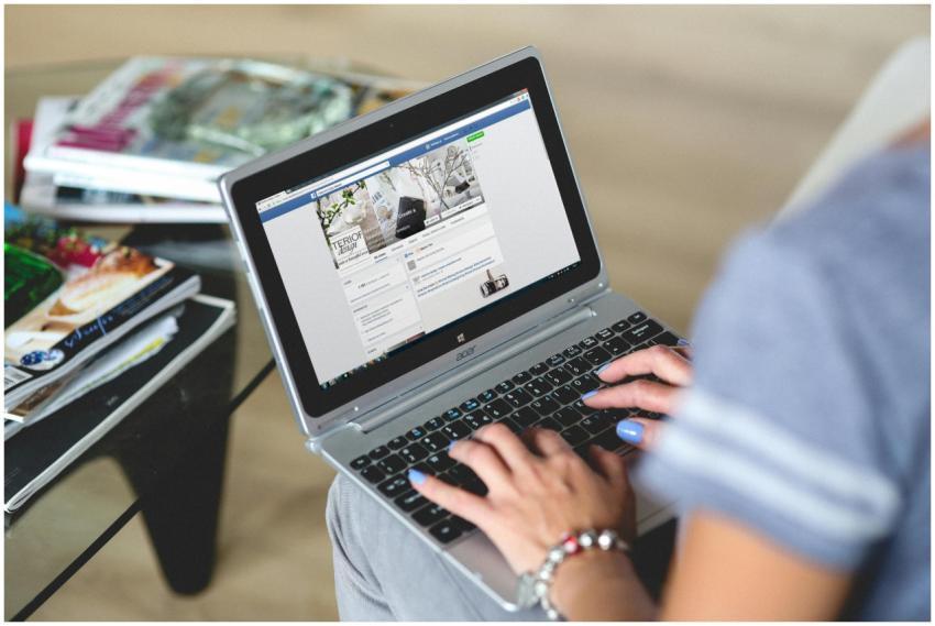 A woman typing on a laptop with social media on th