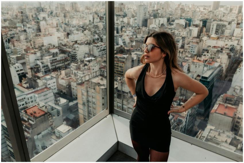 A fashionably dressed woman enjoys a city view fro