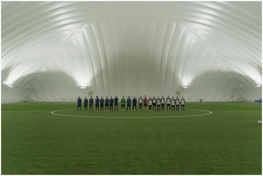 Two soccer teams lined up on an indoor artificial