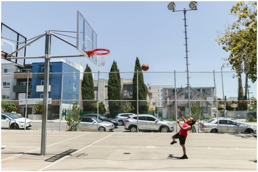 A young boy shoots a basketball on an outdoor cour