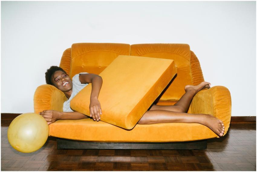 A joyful woman relaxing on a cozy orange sofa with
