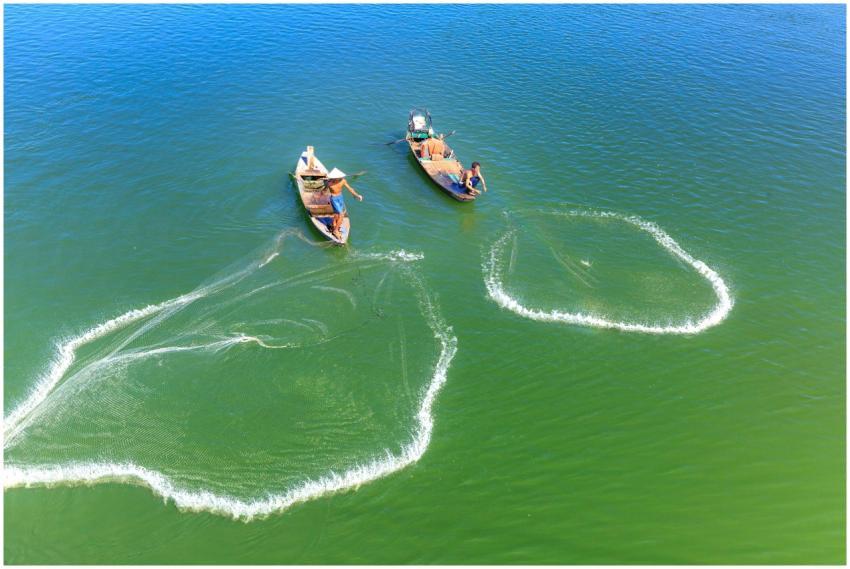 Aerial shot of fishermen on boats casting nets in