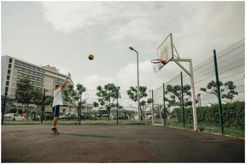 An adult male shooting a basketball on an outdoor