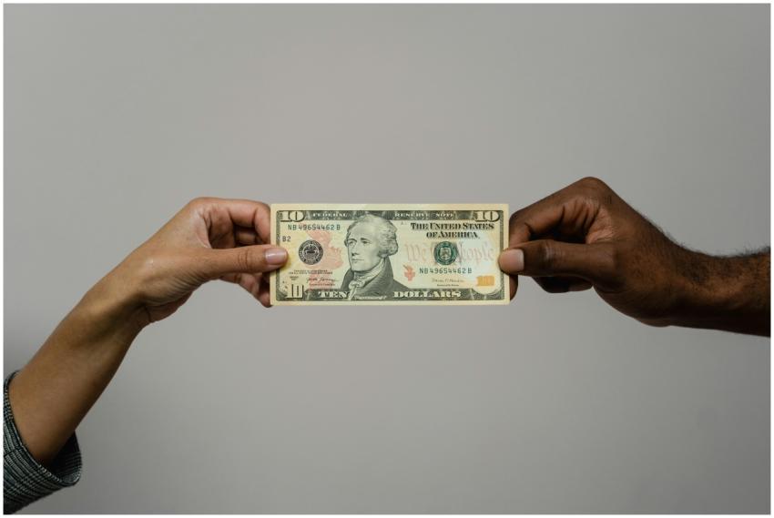 Close-up of two hands exchanging a ten dollar bill