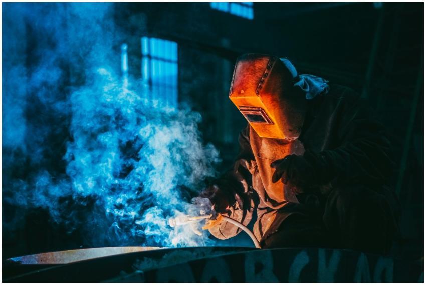 A welder in a workshop using safety gear to weld m