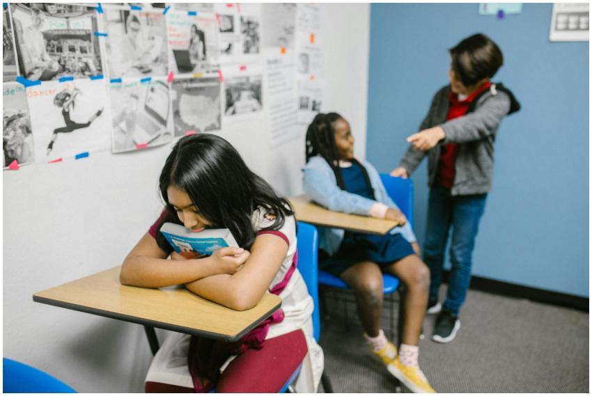 A sad girl in a classroom being bullied by classma