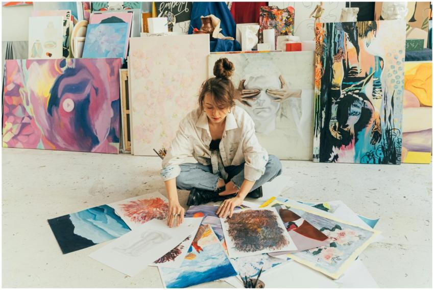 A woman artist organizes her paintings in a vibran