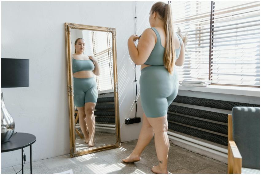 Plus size woman in activewear admiring her reflect