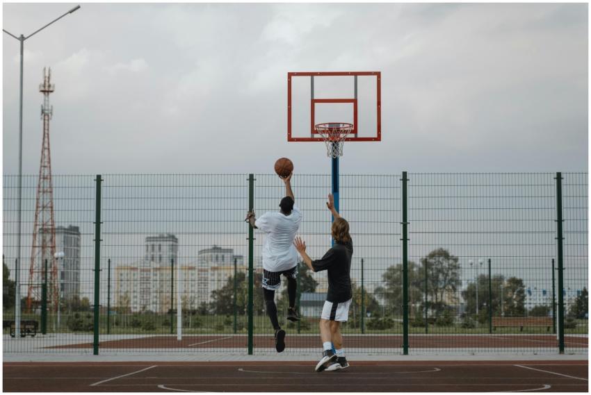 Two adults playing basketball on an outdoor court