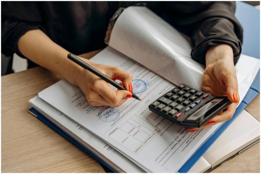 An accountant using a calculator and signing paper