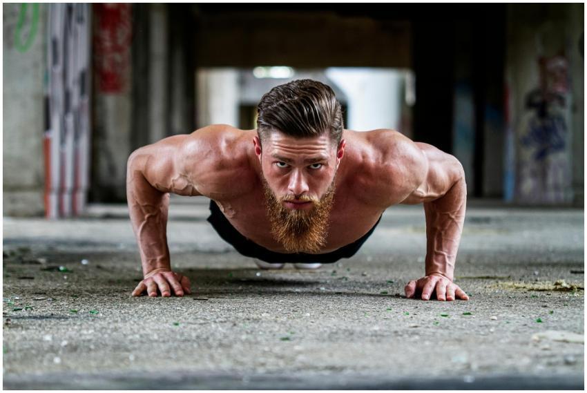 Fit shirtless man with a beard doing a push-up exe