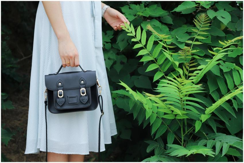 Close-up of a woman holding a black handbag, weari