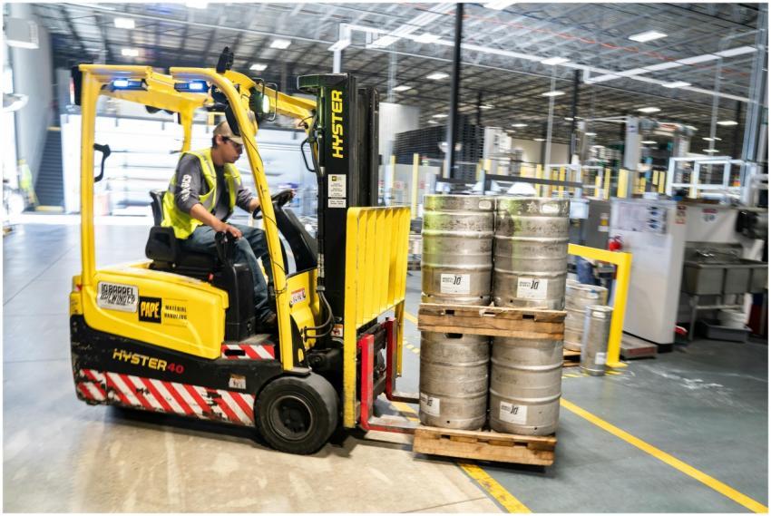 Forklift operator in warehouse moving beer kegs fo