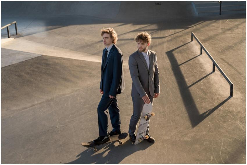 Two men in suits skateboarding at an outdoor skate