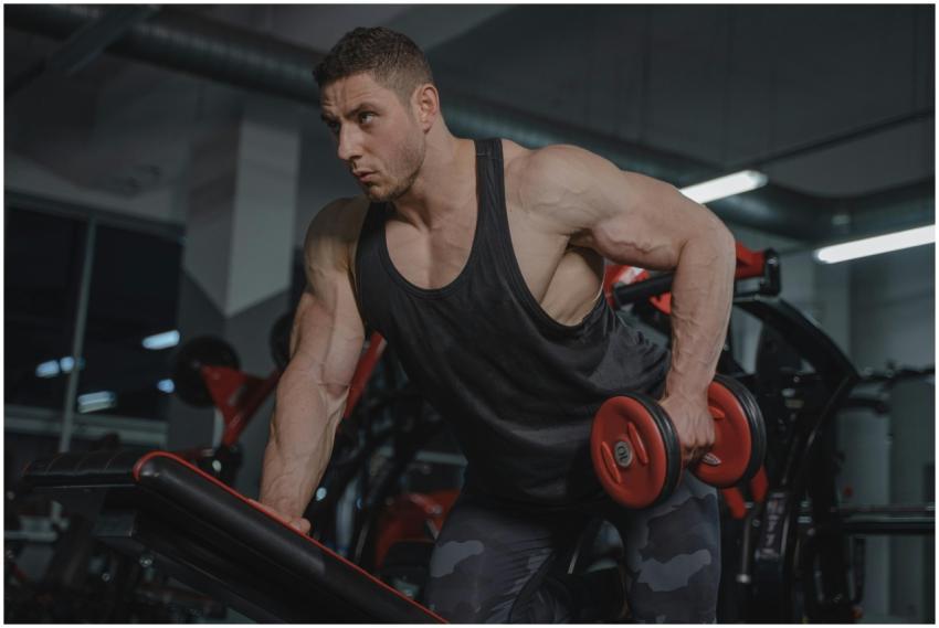 Strong male bodybuilder lifting dumbbells in a gym