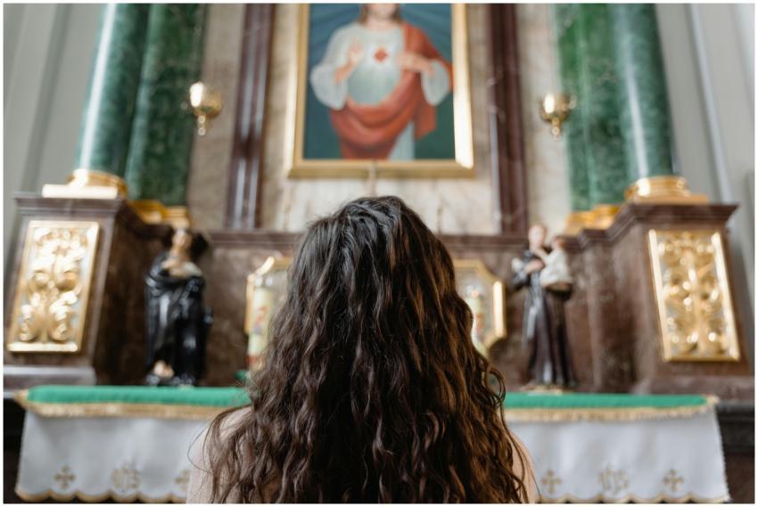 Woman with curly hair kneeling in prayer before an
